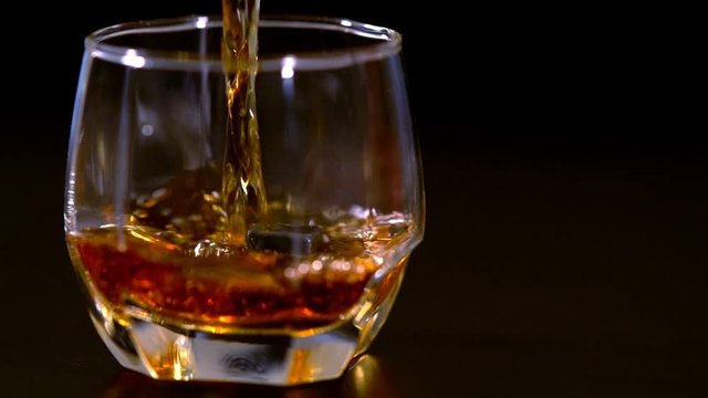 Pouring brandy or whiskey into a glass with ice