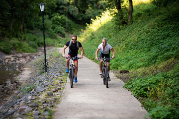 Obraz premium A man and a woman on bikes ride along a path in a park.