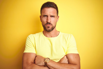 Young handsome man wearing casual yellow t-shirt over yellow isolated background skeptic and...