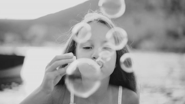 Preteen girl blowing beautiful and colorful soap bubble