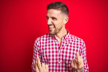 Young handsome man over red isolated background Showing middle finger doing fuck you bad...