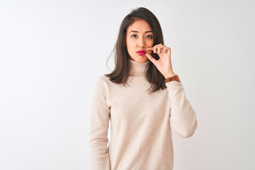 Beautiful chinese woman wearing turtleneck sweater standing over isolated white background mouth and lips shut as zip with fingers. Secret and silent, taboo talking