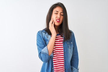 Young chinese woman wearing striped t-shirt and denim shirt over isolated white background touching mouth with hand with painful expression because of toothache or dental illness on teeth. 