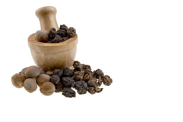 triphala ayurvedic medicinal plant comprise of  chebulic myrobalan fruit, organic amla fruit, and organic belleric myrobalan fruit on white background with copy space, with wood mortar and pestle