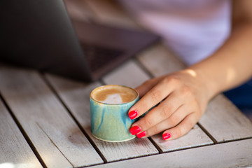 Naklejka na ściany i meble hand holding cup of coffee on wooden table