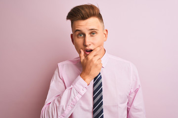 Young handsome businessman wearing shirt and tie standing over isolated pink background Looking fascinated with disbelief, surprise and amazed expression with hands on chin
