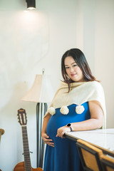 Pregnant woman in dress holds hands