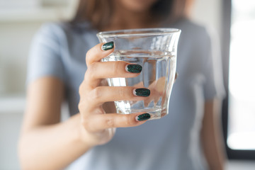 Close up view of young woman drinking pure mineral water in a glass.