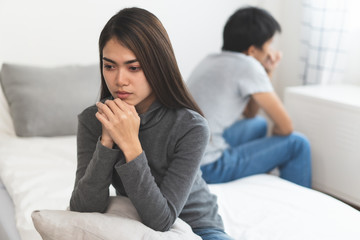 Lover couple relationship problems. Sad young wife sitting on the bed back to back from husband...