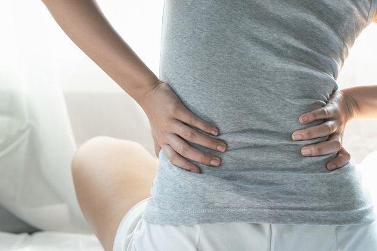 person touching lower back feeling muscle pain at the back.