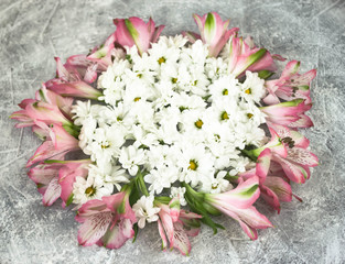 Composition of white chrysanthemum and rose Alstroemeria flowers round circle on grey background floral pattern frame, top view, flat lay