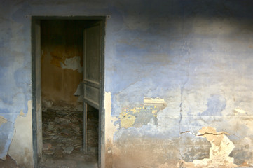 room wall with deteriorated paint and open door