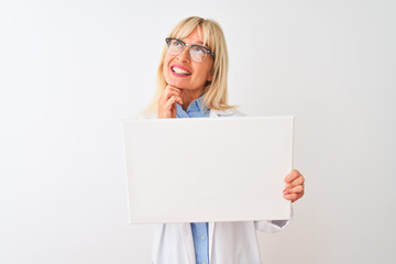 Middle age scientist woman wearing glasses holding banner over isolated white background serious face thinking about question, very confused idea