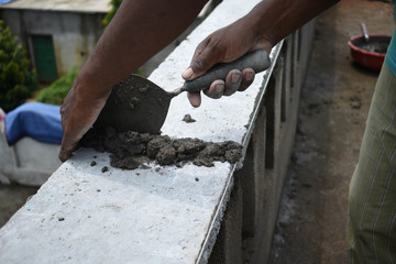 A worker plastering wall with concrete cement mixture using a trowel