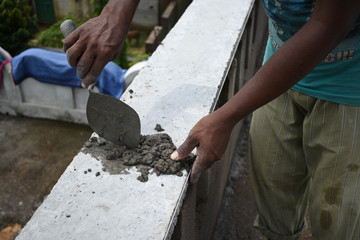 A worker plastering wall with concrete cement mixture using a trowel