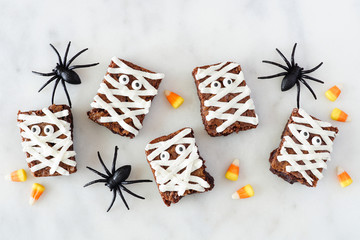Halloween mummy brownies, top view with decor on a white marble background