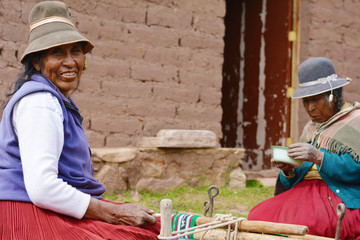 Two native american woman. One of them is eating and another one is weaving.