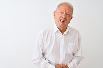 Senior grey-haired man wearing elegant shirt standing over isolated white background with hand on stomach because indigestion, painful illness feeling unwell. Ache concept.