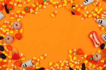 Halloween candy frame. Top view against an orange background with copy space.