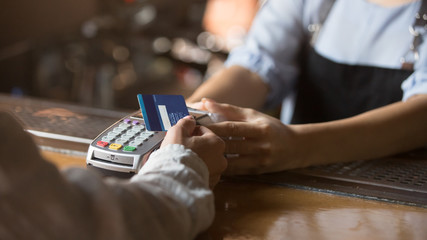 Female customer holding credit card near nfc technology on counter - obrazy, fototapety, plakaty