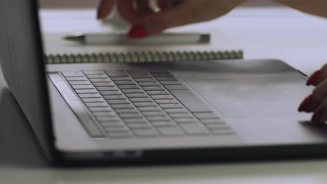 Woman hands with red manicure using laptop to work study and writing on paper with a pen. Business, financial, trade stock maket and social network concept.