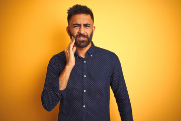 Obraz premium Young handsome indian businessman wearing shirt over isolated yellow background touching mouth with hand with painful expression because of toothache or dental illness on teeth. Dentist concept.