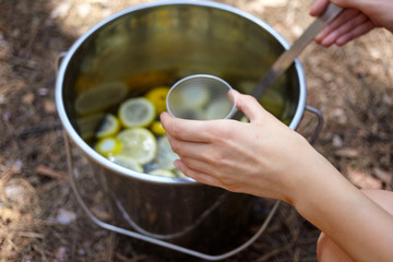 Process of pouring citrus lemonade from bucket in the forest for picnic
