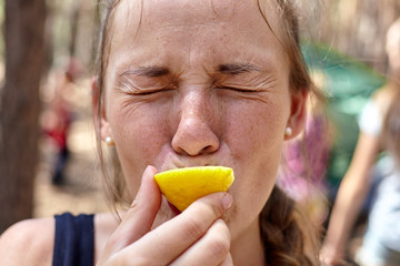Close up photo of girl eating lemon in the forest