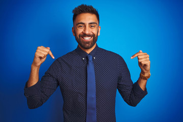 Young indian businessman wearing elegant shirt and tie standing over isolated blue background...