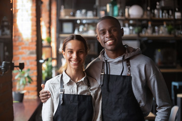Happy diverse waiter and waitress looking at camera in restaurant
