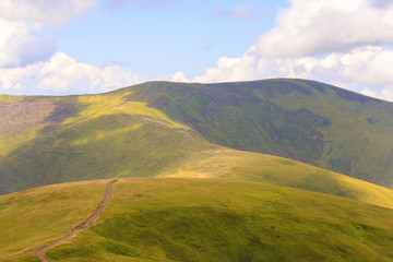 Green mountains with a hiking trail on the background of cloudy sky. Location place Ukraine Carpathian meadow Borzhava.
