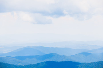 Obraz premium Wspaniały krajobraz z niebieskimi sylwetkami wzgórz i gór z błękitnym niebem. tło