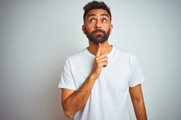 Young indian man wearing t-shirt standing over isolated white background Thinking concentrated...