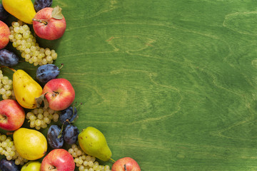 Various seasonal fruits on the green wooden table