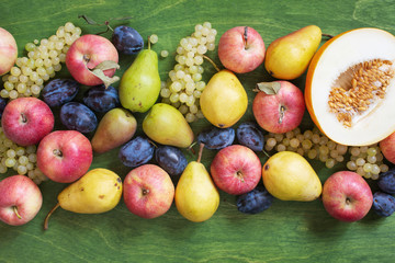 Various seasonal fruits on the green wooden table