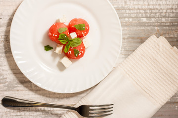 Salad of watermelon balls, feta cheese and mint, sprinkled with sesame seeds in a white plate. Close up
