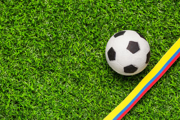 Soccer ball in synthetic grass and flag of Colombia