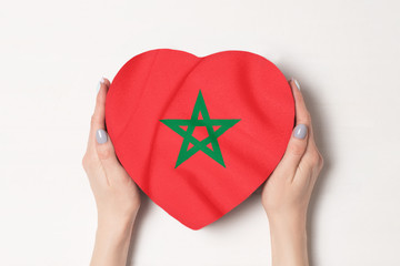 Flag of Morocco on a heart shaped box in a female hands. White background
