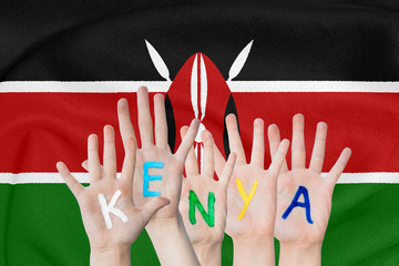 Inscription Kenya on the children's hands against the background of a waving flag of the Kenya