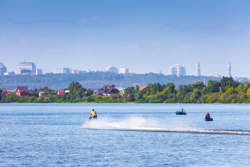 Obraz premium Summer sunny hot evening. Modern residential areas southern suburbs and midtown on hills in Kyiv on the right bank of the Dnipro River. Fishermen on boats on foreground. Kyiv. Ukraine. Aug. 28, 2019