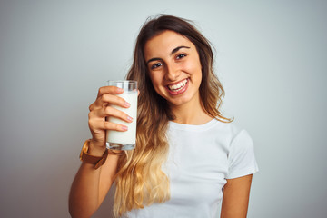 Young beautiful woman drinking a glass of milk over white isolated background with a happy face standing and smiling with a confident smile showing teeth