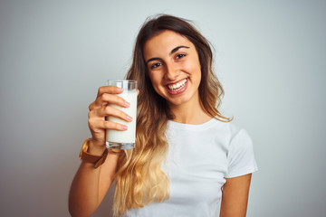 Young beautiful woman drinking a glass of milk over white isolated background with a happy face...