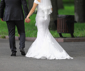 Fototapeta na wymiar bride in a white dress walks along the road