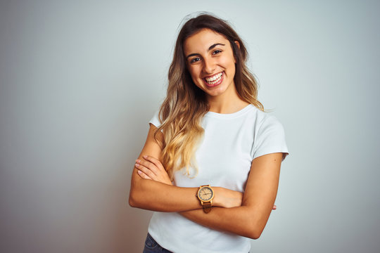 Young beautiful woman wearing casual white t-shirt over isolated background happy face smiling with crossed arms looking at the camera. Positive person.