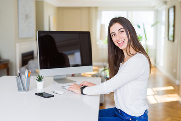 Young woman smiling working using computer and showing a blank screen on the background