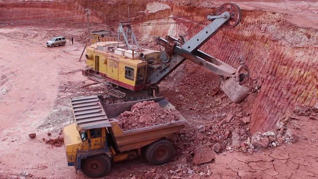 A large mining excavator loads a huge mining truck. Top view, the general plan. A large mountain excavator works.