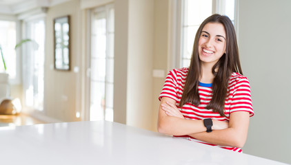 Beautiful young woman wearing casual stripes t-shirt happy face smiling with crossed arms looking at the camera. Positive person.