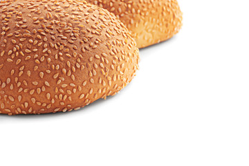 Composition of two partially visible tasty round baked buns with sesame seeds for sandwiches with empty space for text isolated on white background