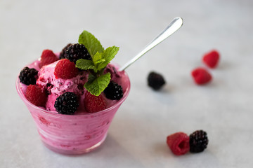 Homemade sorbet made from fresh berries with mint in glass bowl on a gray background.