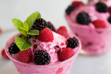 Homemade sorbet made from fresh berries with mint in glass bowl on a gray background.